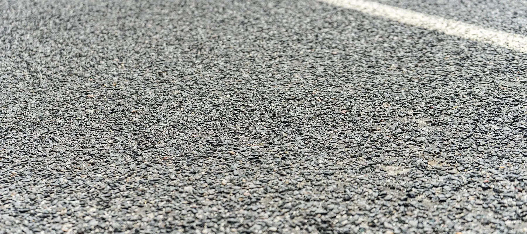 A clean, newly paved commercial parking lot displaying pristine asphalt and professional concrete curb installations.