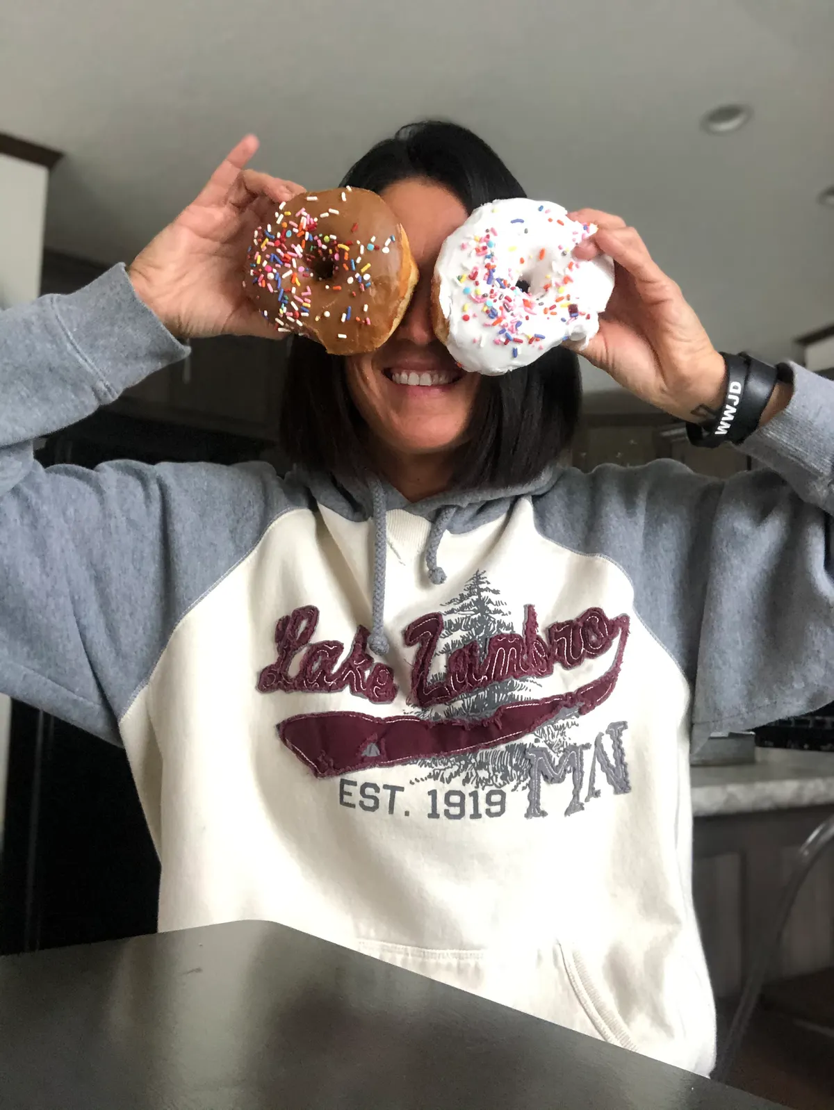 A Triton team member holding two frosted donuts up in front of her eyes