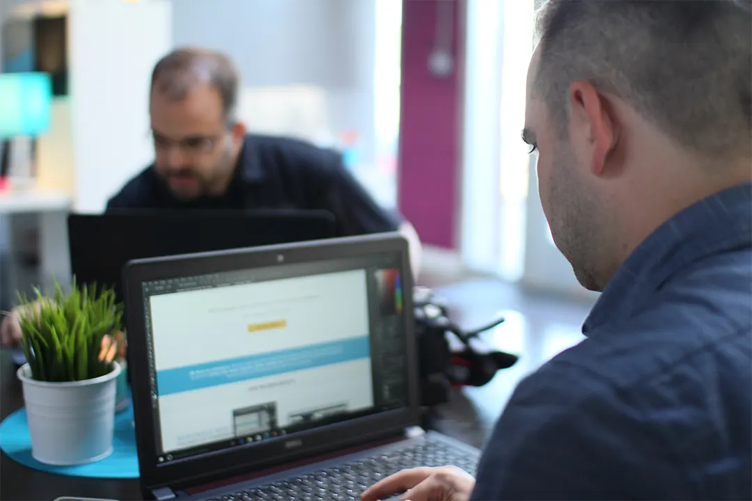 Two Triton team members reviewing a client website together on a laptop